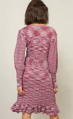 Load image into Gallery viewer, Back full body view of a woman with wearing the Line + Dot Noa Sweater Dress. This dress has a mixed pink and blue knit fabric, a fitted silhouette with a ruffled hem that sits at the knees and large sleeves with fitted cuffs.
