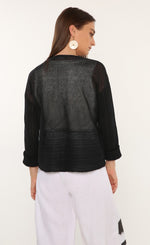 Load image into Gallery viewer, Back top half view of a woman wearing the ozai n ku mimosa knit top. This top is black and translucent. It has a darker pattern running across the bottom of the back and on the long sleeves. 

