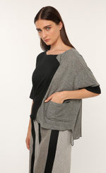 Load image into Gallery viewer, Front top half view of a woman wearing the ozai n ku vervain top. This top is black on the front right side and dark grey on the front left side. The sleeves are elbow length and the two tones come together to create a fold over effect near the neck. The front also has a front pocket on the left side.
