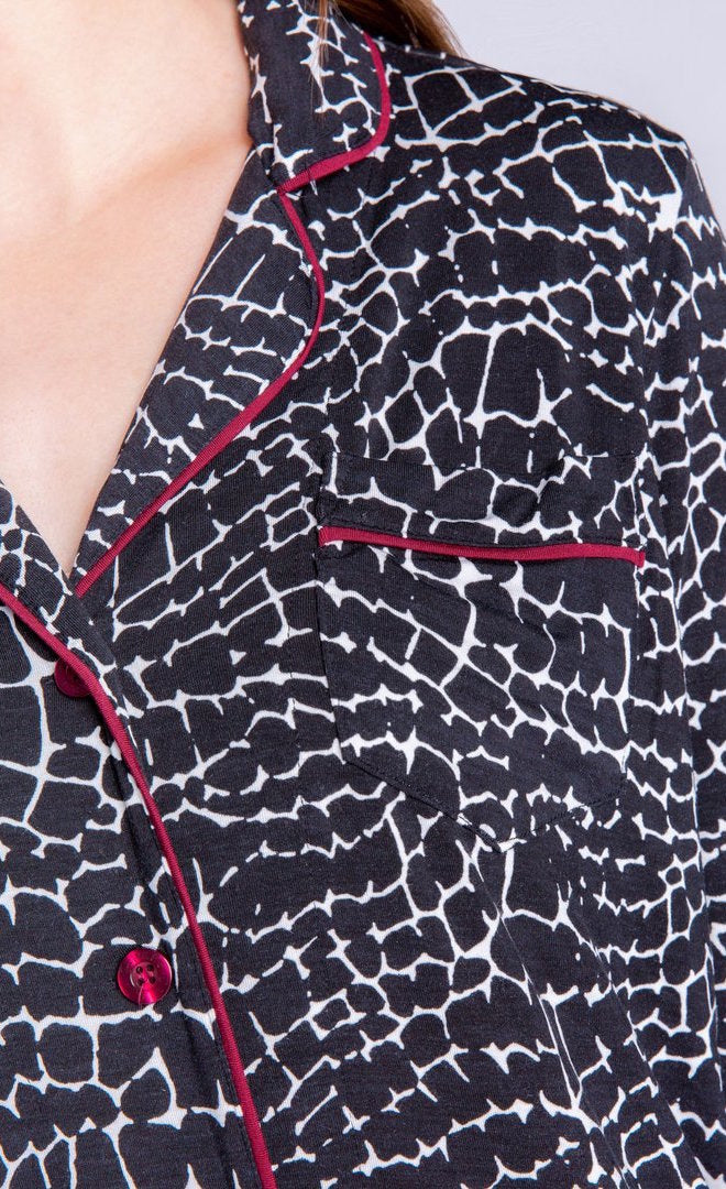 Close up front view of a woman wearing the PJ salvage croc hideaway nightshirt. This nightshirt is black with white crocodile print all over it and bordeaux piping along the button down front. 