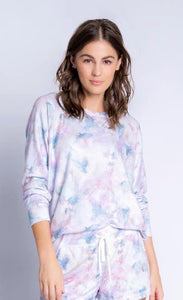 Front top half view of a woman wearing the PJ Salvage Marble top. This top has a soft pink and blue marble print and long sleeves. On the bottom the woman is wearing a matching PJ salvage marble banded pant.