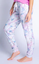 Load image into Gallery viewer, Side bottom half view of a woman wearing the PJ Salvage Marble Banded pant. This pant has a soft pink and blue marble pattern and a white tie-waistband.
