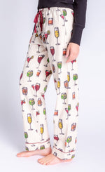 Load image into Gallery viewer, Left side Bottom half view of a woman wearing the pj salvage call me old fashioned flannel pj set. The model has on an ivory colored long pant with cocktail glasses all over it and a wine colored drawstring waistband.
