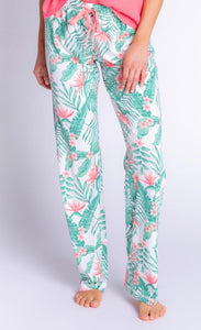 Front bottom-half view of a woman wearing the pj salvage playful prints pant. The bottoms are white with green palm leaves and coral detailing/a coral drawstring.