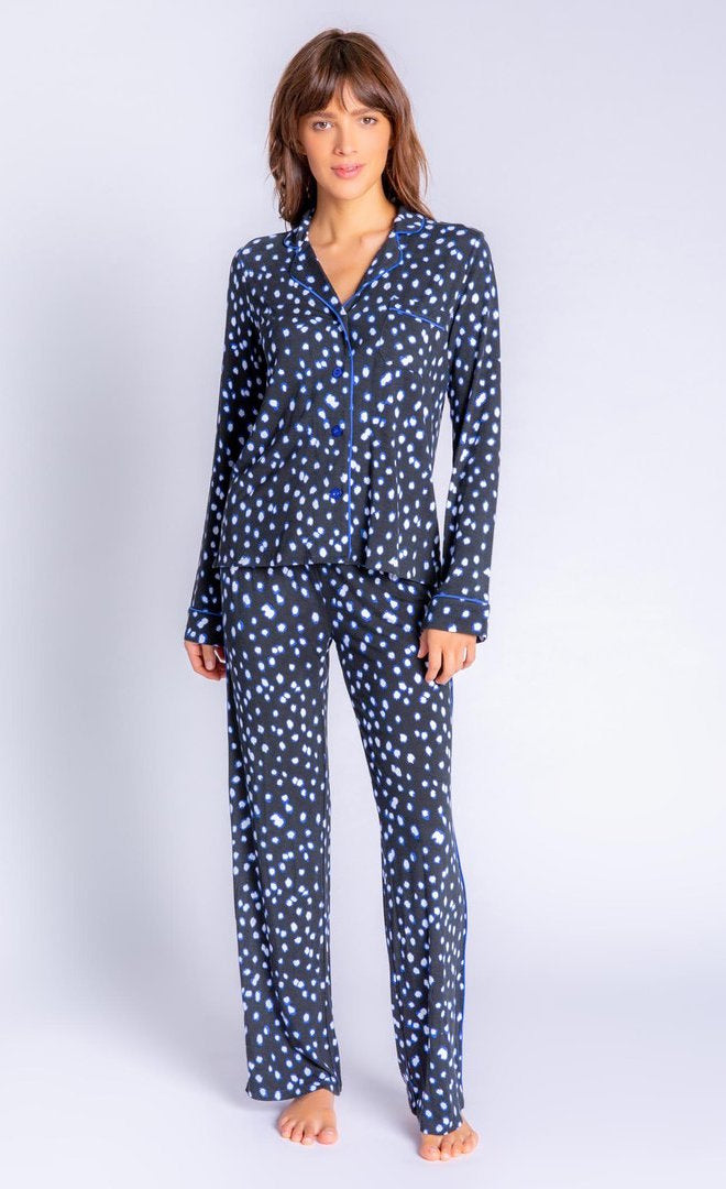 Front full body view of a woman wearing the pj salvage spot the dot pj set. This set is a long sleeve shirt and long pant. It is black with white dots lined in blue.
