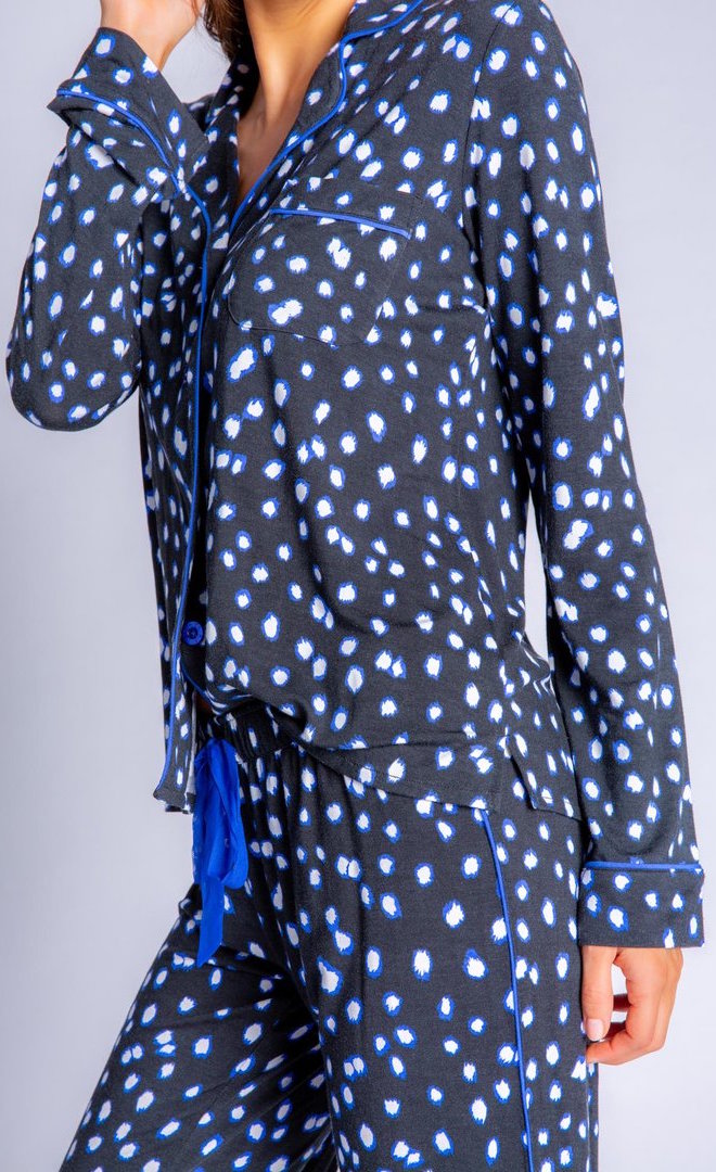 Front close up view of a woman wearing the pj salvage spot the dot pj set. This set is a long sleeve shirt and long pant. It is black with white dots lined in blue.