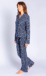 Load image into Gallery viewer, Front full body view of a woman wearing the pj salvage spot the dot pj set. This set is a long sleeve shirt and long pant. It is black with white dots lined in blue.

