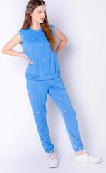 Load image into Gallery viewer, Front full body view of a woman wearing the pj salvage sun out tank and the pj salvage sun out banded pant. The pant and tank are both sky blue with tiny embroidered sunsets all over it.
