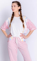 Load image into Gallery viewer, Front top half view of a woman wearing the PJ Salvage Sunset Hues short sleeve top and the pj salvage sunset hues banded pant. The top is white with yellow, blue, and pink tie dye on the sides. The bottoms are pink with crochet detailing on the sides and a banded hem. 
