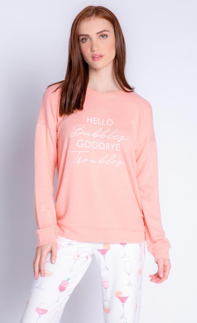 Front top half view of a woman wearing the peach sunset spritzer long sleeve top. This top says hello bubbles, goodbye troubles.