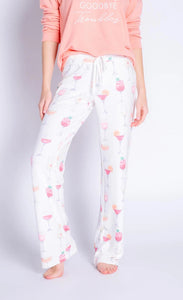 Bottom half view of a woman wearing the ivory sunset spritzers pant. This pant has a orange and pink cocktail print.