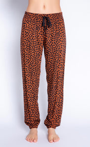 Front view of the bottom half of a woman wearing the PJ Salvage Wild Love Banded Pant. This banded pant is mocha/brown colored with a black heart shaped animal print. It has a black tie waistband.