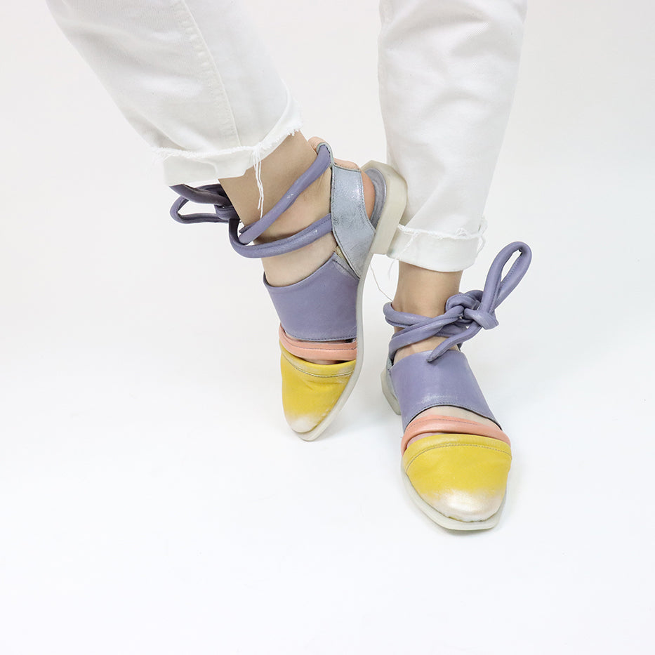 Outer and inner side view of a pair of the papucei etsy shoe. This shoe is flat. The front leather portion that covers the toe is yellow. The strap over the inset is pink and the rest of the shoe leather is purple. This shoe also has purple leather ankle ties.