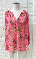 Load image into Gallery viewer, front view of a mannequin wearing the part two erdonae paisley flower blouse. This blouse is bright pink with black and gold paisley floral print on it. The top has a v-neck and long sleeves with cuffs.
