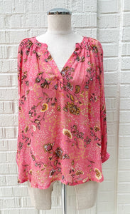 front view of a mannequin wearing the part two erdonae paisley flower blouse. This blouse is bright pink with black and gold paisley floral print on it. The top has a v-neck and long sleeves with cuffs.