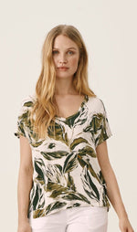 Load image into Gallery viewer, Front top half view of a woman wearing the part two icalina t-shirt. This t-shirt has a mixed green palm leaf print, short sleeves, and a v-neck.
