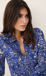 Load image into Gallery viewer, front close up view of a woman wearing the part two true paisley flower dress. This dress is ultramarine/vibrant blue color with white paisley floral print. The dress has a button down front.
