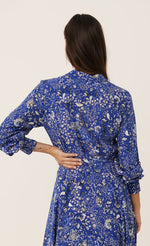 Load image into Gallery viewer, Back full body view of a woman wearing the part two true paisley flower dress. This dress is ultramarine/vibrant blue color with white paisley floral print. The dress has a tie belt at the waist.
