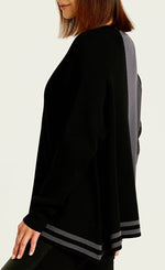Load image into Gallery viewer, left side top half view of a woman wearing black leather pants and the planet pima cotton 2 tone crewneck sweater. This sweater is black on the left side and grey on the right side. the left side also has a longer hem with grey striping, while the right side has a shorter hem with a washed black sleeve.
