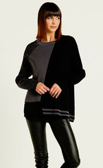 Load image into Gallery viewer, front top half view of a woman wearing black leather pants and the planet pima cotton 2 tone crewneck sweater. This sweater is black on the left side and grey on the right side. the left side also has a longer hem with grey striping, while the right side has a shorter hem with a washed black sleeve.
