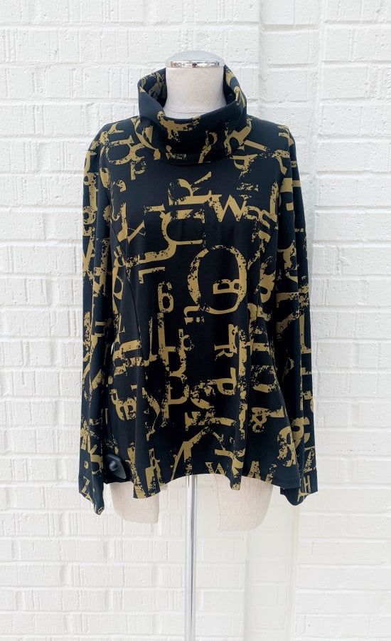 Front view of the porto tucker top. This top is black with a dijon yellow newspaper letter print. It has long sleeves and a turtleneck.