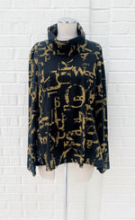 Load image into Gallery viewer, Front view of the porto tucker top. This top is black with a dijon yellow newspaper letter print. It has long sleeves and a turtleneck.

