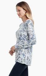 Load image into Gallery viewer, Left side view of a woman wearing the Nic+Zoe Scribbled Up Top. This top has a blue abstract scribble print, long sleeves, and a boat neck.
