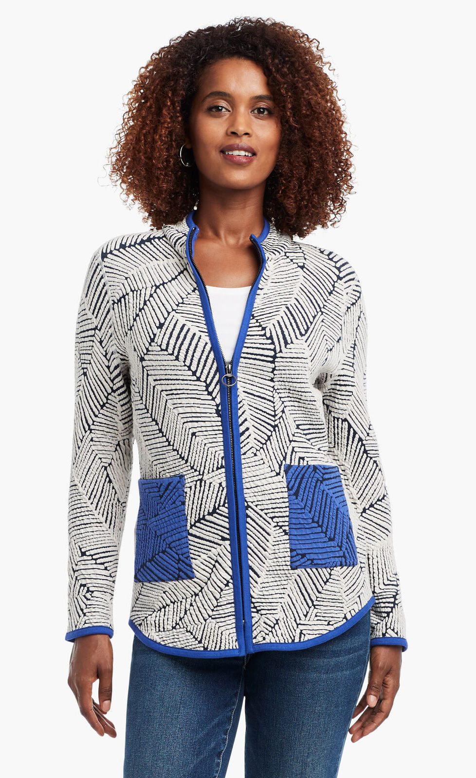 Front view of a woman wearing the Nic+Zoe New Leaf Jacket zipped close. The zip up jacket has a black and white leaf pattern and blue trim with two front blue patch pockets. 