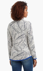 Back view of a woman wearing the Nic+Zoe New Leaf Jacket. The zip up jacket has a black and white leaf pattern and blue trim.