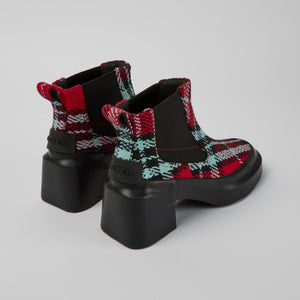 Back view of a pair of the camper blanket/rain multicolor boot. These boots have a chelsea style with elastic sides. The boots have a red, black, and blue plaid print and a chunky black heel.