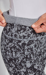 Load image into Gallery viewer, Close up, side view of the waistband of the Lysse Reversible Cotton Legging. The legging has a grey and black speckled print. The woman is folding over the waistband to show the solid grey reversible side.
