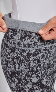 Close up, side view of the waistband of the Lysse Reversible Cotton Legging. The legging has a grey and black speckled print. The woman is folding over the waistband to show the solid grey reversible side.