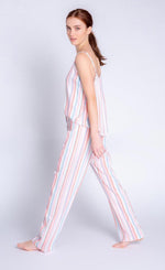 Load image into Gallery viewer, Left side full body view of a woman wearing the saturday morning stripe set. This set includes the saturday morning stripe tank and the saturday morning stripe pant. This pj set is multicolored striped.
