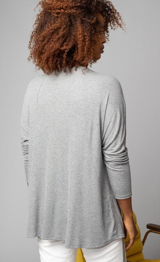 Back, top half view of a woman wearing the grey Lola & Sophie scoop neck shirttail tee. This shirt has a boxy silhouette and fitted sleeves.