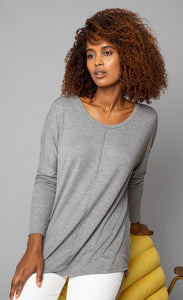 Front, top half view of a woman wearing the grey Lola & Sophie scoop neck shirttail tee. This shirt has a boxy silhouette, indent detailing around the neck and down the front, and fitted sleeves.