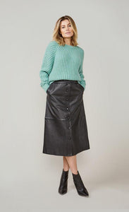 Front full body view of a woman wearing skirts and the summum alpaca wool blend sweater in seafoam green. This sweater has long sleeves and a chunky knit appearance. 
