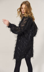 Load image into Gallery viewer, Back full body view of a woman wearing the summum fluffy dress in black. This dress has sparkly fringe on a chevron pattern and ends slightly above the knees.
