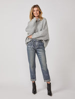 Load image into Gallery viewer, Front full body view of a woman wearing a grey sweater and the summum straight blue daze denim pants. These jeans are blue-grey with a shimmer. They have a cropped and cuffed bottom, pockets, and a tie belt.
