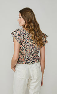 Back top half view of a woman wearing the summum animal print t-shirt with white capris. The T-shirt has short cap sleeves and a pink and navy animal print all over it.