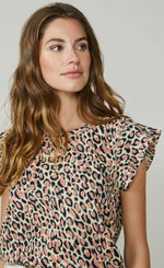 Load image into Gallery viewer, Front close up view of a woman wearing the summum animal print t-shirt. The T-shirt has short cap sleeves and a pink and navy animal print all over it.
