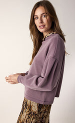 Load image into Gallery viewer, Left side top half view of a woman wearing the summum scuba pullover. This pullover is mauve colored, has drop shoulders, long puff sleeves, and cuffs. The top also has a boat neck.
