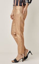 Load image into Gallery viewer, Left side bottom half view of a woman wearing a black, pink, and white striped shirt and the summum skinny foil coated trousers. These trousers are rose gold colored.

