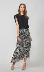 Load image into Gallery viewer, Front full body view of a woman wearing the summum shoulder pad top. This top is sleeves and black with a v-like shape. On the bottom the woman is wearing the summum printed maxi skirt. This skirt has a black and white snakeskin print.
