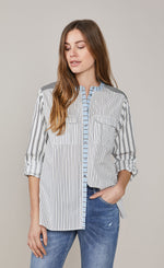 Load image into Gallery viewer, Front top half view of a woman wearing the summum mixed stripes blouse. This blouse has a button down front, rolled up sleeves, and two breast pockets. The shirt has different black stripes on a white background with hints of blue.
