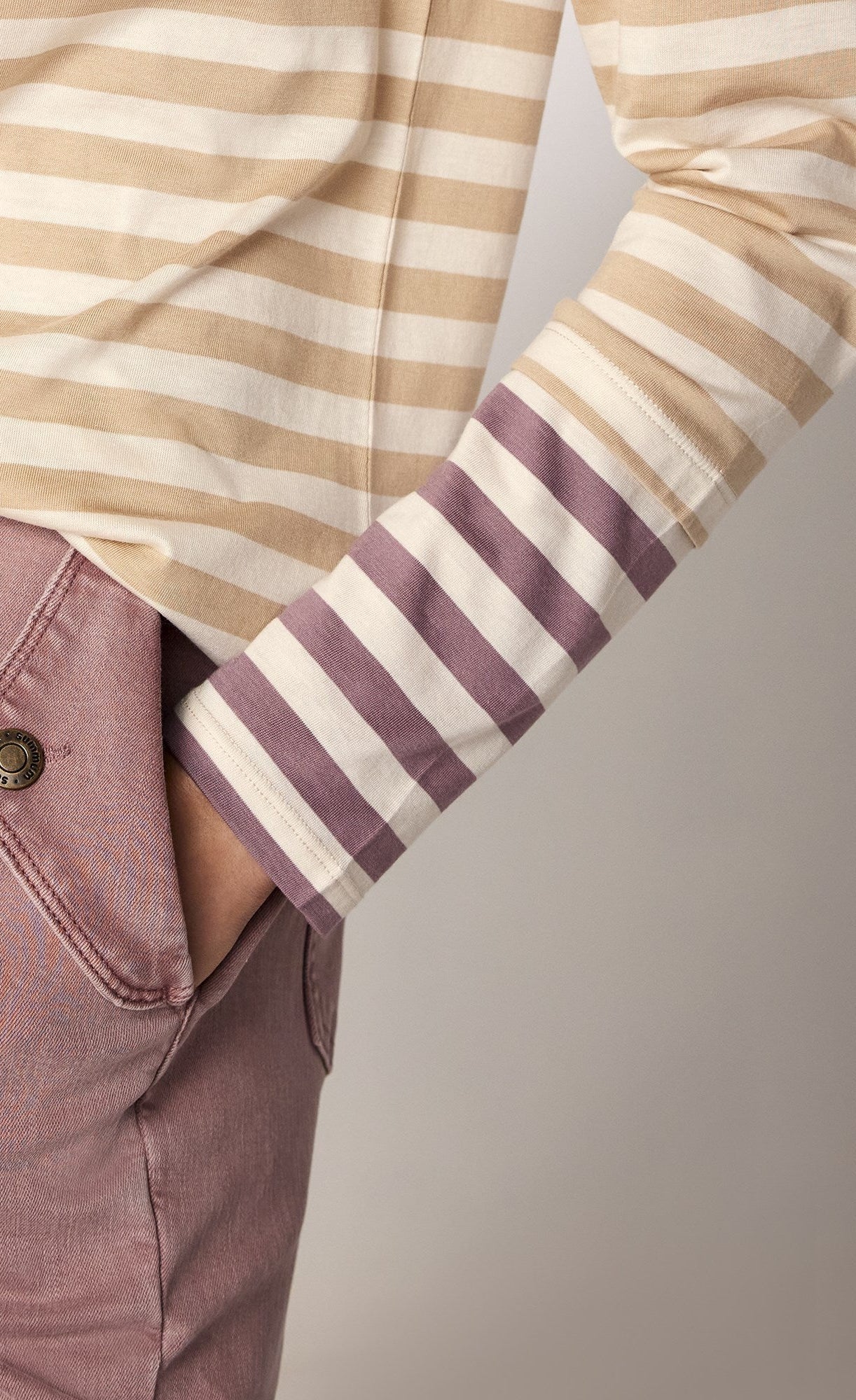 front close up view of the summum striped tone-on-tone shirt. This top has neutral brown stripes with contrasting purple stripes on the end of the long sleeves. The top also has a slight funnel neck.