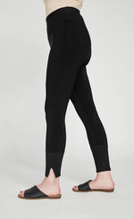 Load image into Gallery viewer, Bottom half left side view of the sympli motion trim cuff legging. This legging is black with a yoke waistband and a ribbed cuff that has a tiny side slit.
