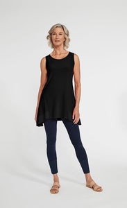 Front full body view of a woman wearing blue leggings and the sympli motion trim tank. This sleeveless tank is black with a round neck and a flared out hem that sits below the hips.