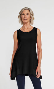 Front top half view of a woman wearing blue leggings and the sympli motion trim tank. This sleeveless tank is black with a round neck and a flared out hem that sits below the hips.