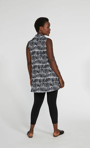 Back full body view of a woman wearing black leggings and the sympli sleeveless double take tunic. This tunic has a black and white shifted stripe print. The hem sits below the hips.