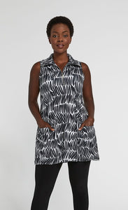 Front top half view of a woman wearing black leggings and the sympli sleeveless double take tunic. This tunic has a black and white shifted stripe print, two front pockets, and a zip neck with a collar.